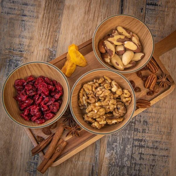 Mixed nuts and dried fruits in wooden bowl on wood background, copy space