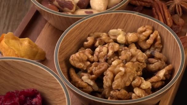 Mixed nuts and dried fruits in wooden bowl on wood background, copy space — Stock Video