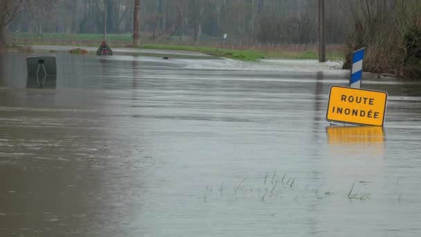 Water over de weg, weg overstroomd door overstroming van een rivier en gevaarsteken — Stockvideo