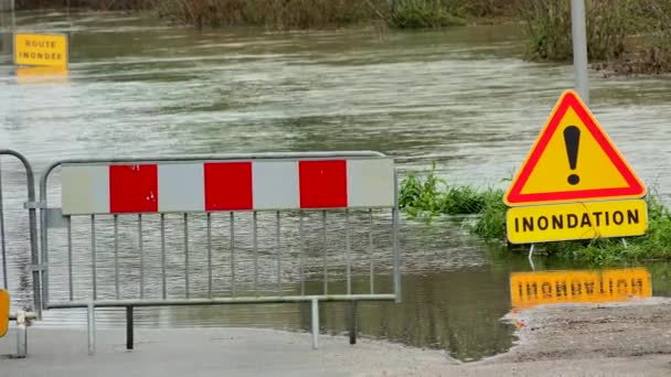 Vatten över väg, väg översvämmad av översvämning av en flod och vägskylt fara — Stockvideo