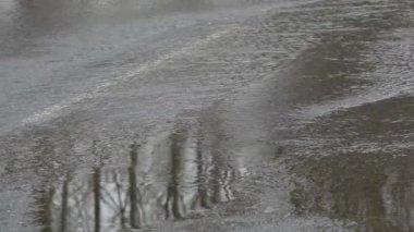 Yolun üstünde su, yol taşmış bir nehir ve tehlike işareti.