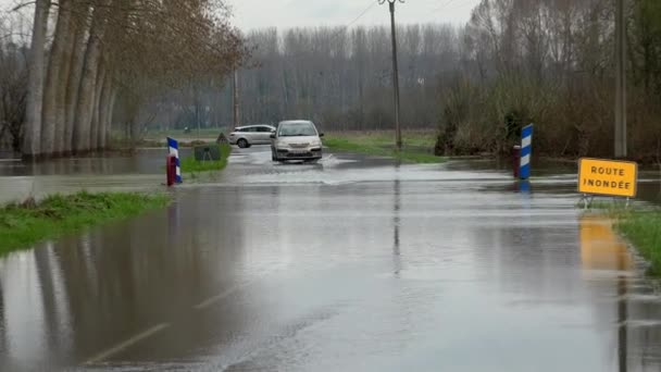 Вода над дорогой, Дорога затоплена переливом реки и знаком опасности — стоковое видео