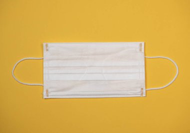 Virüs salgını sırasında koruyucu tıbbi ekipman, sarı arka planda cerrahi maske.