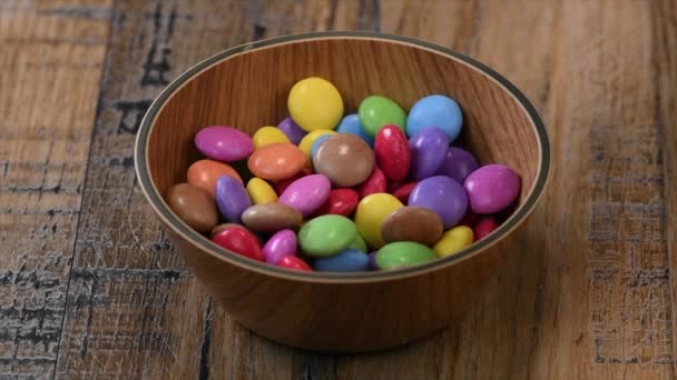 Slow motion, Colorful candies in a wooden bowl case isolated on wood background — Stock Video