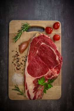 Tahtadaki çiğ T-Bone bifteği ızgaraya hazır. 