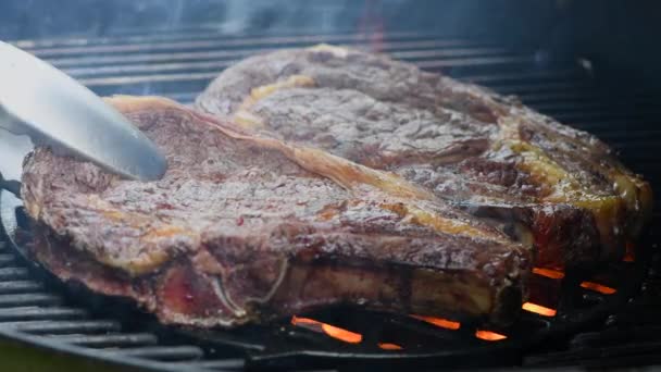 用焦炭和火焰加热烤架上的大块多汁牛肉条眼牛排 — 图库视频影像