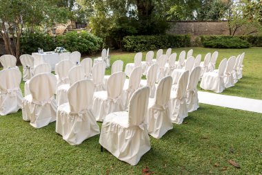 Yeşil çimenlikte beyaz düğün sandalyeleri 