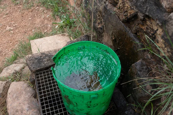 Su musluğu ve yeşil kovası olan dağ manzarası