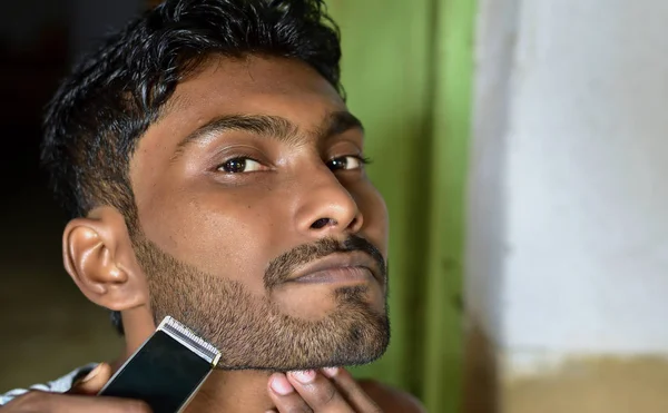 전기 철공으로 수염을 깎고 있는 한 젊은 남자의 모습 — 스톡 사진