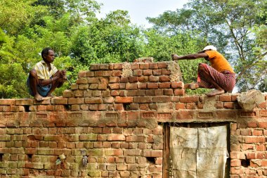 Jhargram, Hindistan - Kasım: Hintli adam çekiçle tuğla bir duvar kırıyor, evini inşa ediyor ve onarıyor.