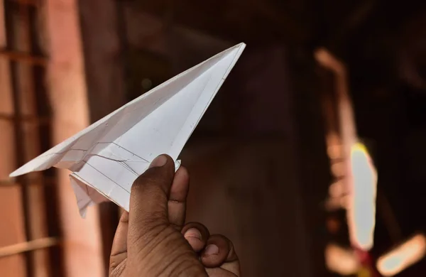 Gros plan de la main d'un enfant sur le point de jeter un avion en papier fait avec un papier imprimé. concept de voler à travers la fenêtre et embrasser le monde extérieur . — Photo