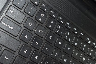 Side photo of a laptop keyboard showing brushed black surface. Technology concept. selective focus.