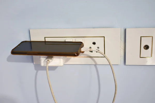 El teléfono móvil que carga la batería con las luces en la pared — Foto de Stock