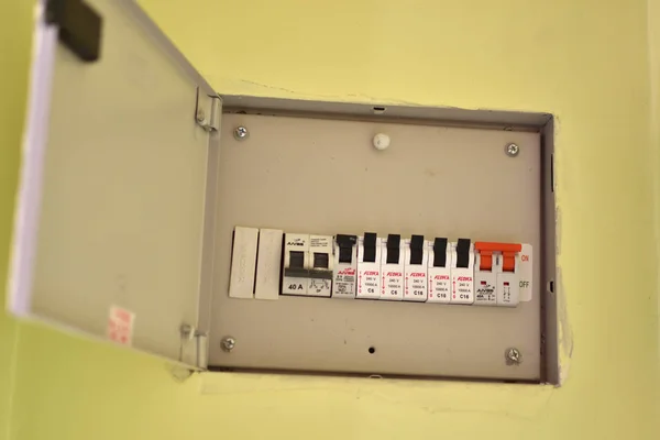 Voltage switchboard with circuit breakers. A finger is about to switch off a large red MAINS switch on an RCD circuit breaker. Circuit breaker type electric 3 phase was installed on the wall.