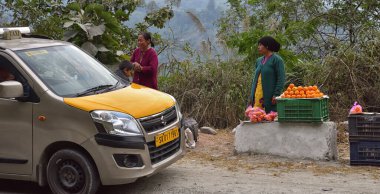 Dağ yolunda farklı meyveleri olan bir meyve dükkanının yanında araba duruyor. arka plan olarak güzel bir manzara