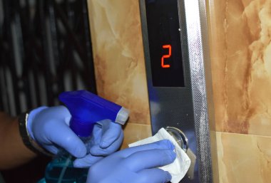 Coronavirus ya da COVID-19 önleme asansör düğmelerini temizlemek ve halka açık alanlara dokunmak. Bina kaldırma düğmesine basarak korona virüsünü öldürmek için antibakteriyel dezenfekte beziyle silmek. seçici odak