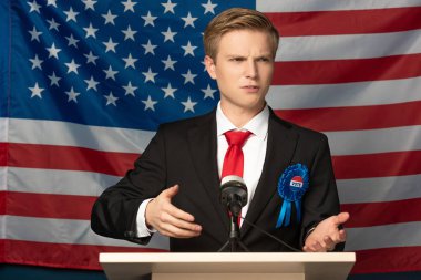 emotional man on tribune during speech on american flag background