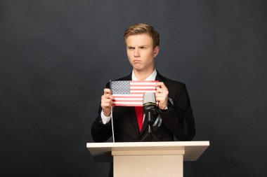 Siyah arka planda Amerikan bayrağı olan kızgın duygusal adam tribünde