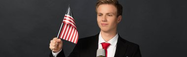 Siyah arka planda Amerikan bayrağı taşıyan gülümseyen duygusal adam.