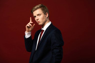 Kendine güvenen adam kırmızı arkaplanda fikir jesti gösteriyor