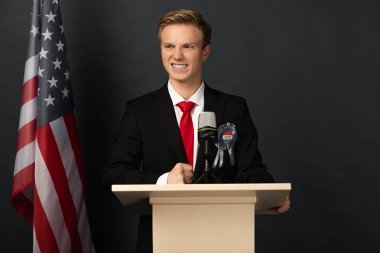Siyah arka planda Amerikan bayrağı olan mutlu duygusal adam tribünde