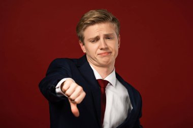 displeased man showing thumb down on red background clipart
