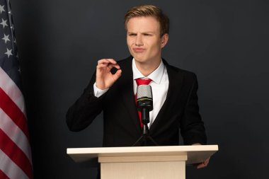 Duygusal adam siyah arka planda Amerikan bayrağıyla Tribünde Tamam işareti gösteriyor