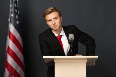Siyah arka planda Amerikan bayrağıyla Tribünde hoşnutsuz duygusal bir adam