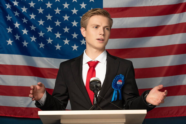 man speaking on tribune on american flag background