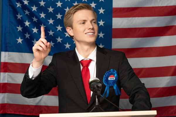 smiling man showing idea gesture on tribune on american flag background