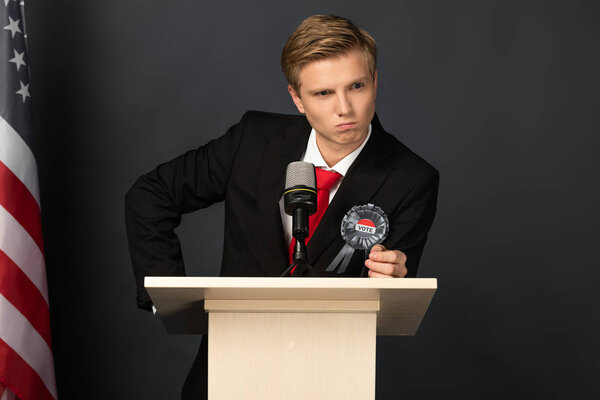 angry emotional man on tribune with american flag on black background