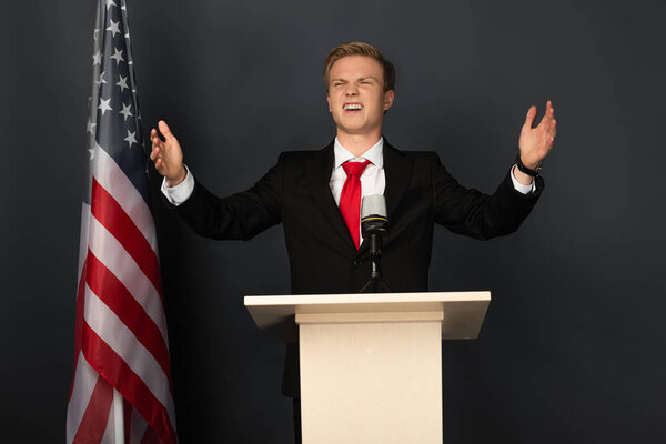 happy emotional man on tribune with american flag on black background