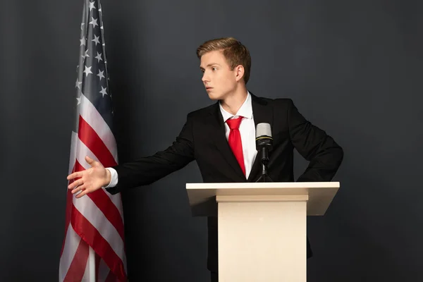 Uomo Emotivo Parlando Gesticolando Tribuna Con Bandiera Americana Sfondo Nero — Foto Stock