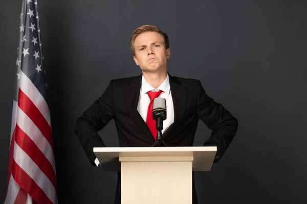 confident emotional man on tribune with american flag on black background