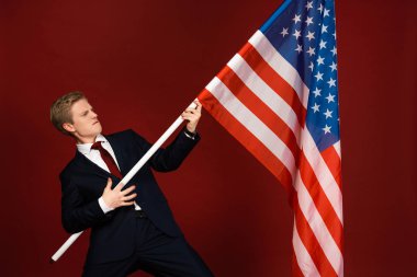 Kırmızı arka planda Amerikan bayrağı tutan duygusal adam