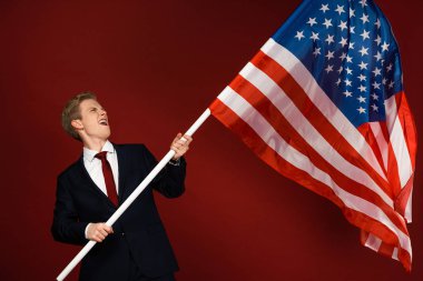 Kırmızı arka planda Amerikan bayrağı tutan duygusal adam