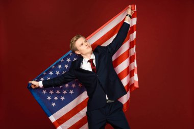 Kırmızı arka planda Amerikan bayrağı tutan hayalperest adam.