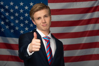 Amerikan bayrağı geçmişinde baş parmağını gösteren bir adam.