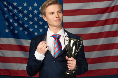 man holding golden goblet on american flag background clipart