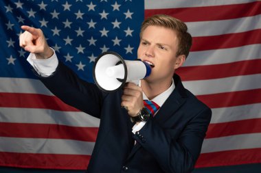 Amerikan bayrağı arka planında megafonla bağıran adam.