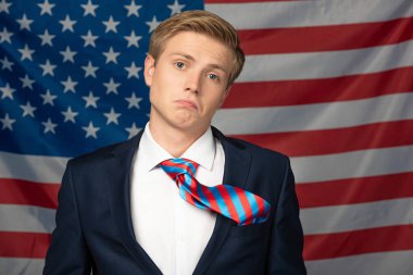 Amerikan bayrağı geçmişinde asık suratlı bir adam.
