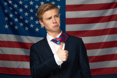 Amerikan bayrağı geçmişinde baş parmağını gösteren bir adam.