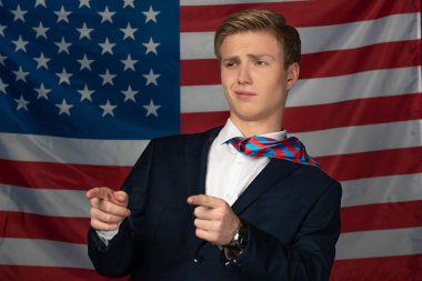 Amerikan bayrağı arka planında parmaklarını gösteren bir adam.