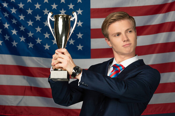 man holding golden goblet on american flag background