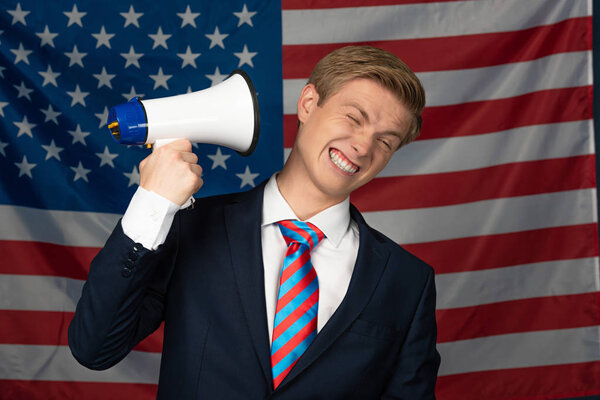 man shouting in megaphone on american flag background