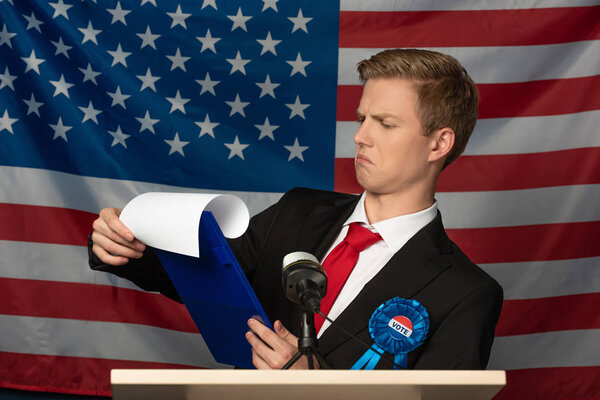 emotional man looking at clipboard on tribune on american flag background