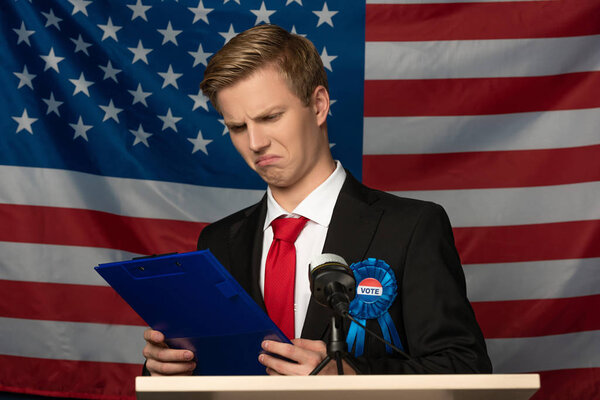 emotional man looking at clipboard on tribune on american flag background