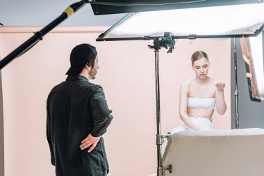 Fotoğraf stüdyosunda spot ışıkları olan güzel bir model ve kameraman.