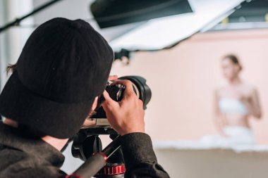 Fotoğraf stüdyosundaki kamera ve kadın modelin arka görüntüsü.