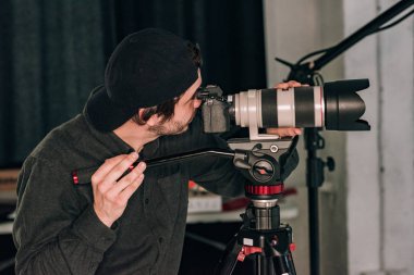 Side view of videographer working with camera in photo studio clipart